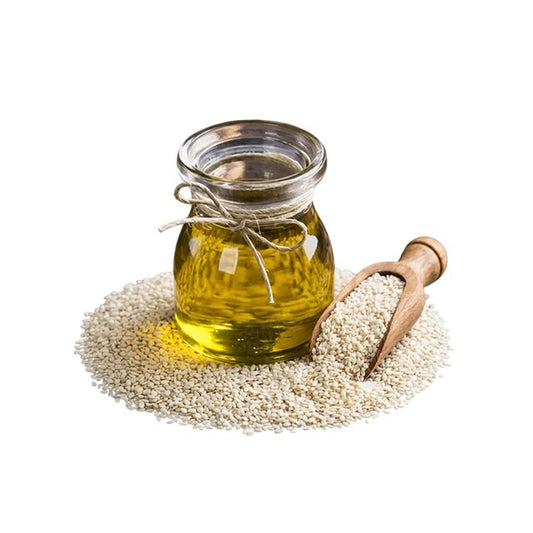 A small clear glass jar filled with golden yellow oil, tied with twine, set on a pile of white sesame seeds with a wooden scoop beside it on a white background.